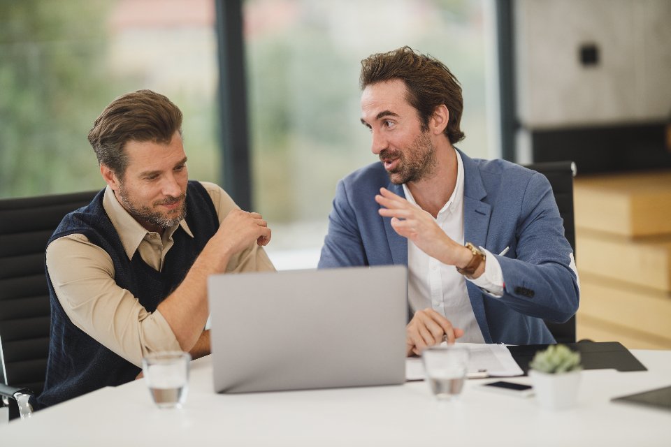 Two IT professionals discussing and reviewing code on a laptop